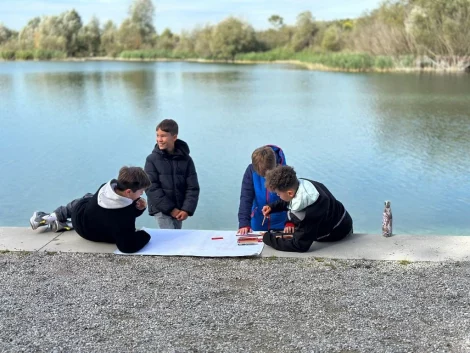crianças a desenhar junto a um lago